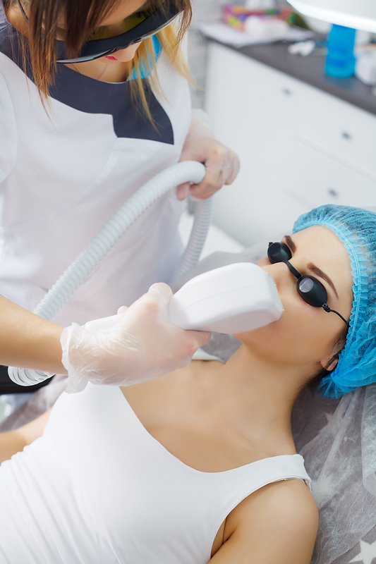 The doctor-cosmetologist makes the procedure Microcurrent therapy of the facial skin of a beautiful, young woman in a beauty salon.Cosmetology and professional skin care.